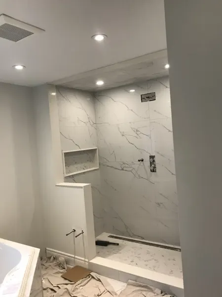 Shower tile installed while fittings and enclosure remain in progress